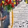 A visitor raising his hands in dua beside a flower-decorated shrine