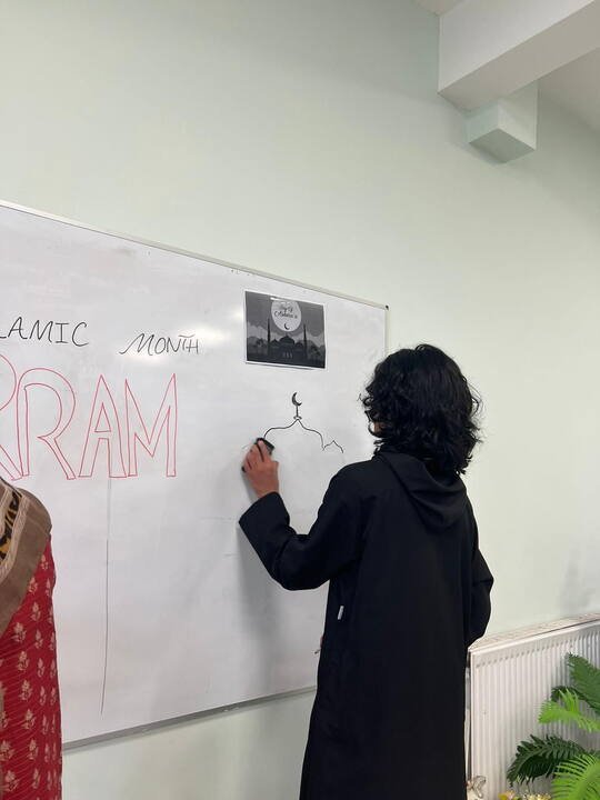 Teacher writing on a whiteboard during a class at BKM Community